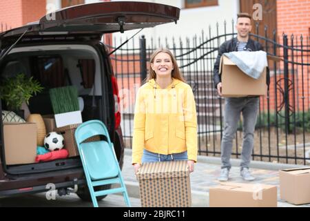 Young couple unloading boxes from their car on moving day Stock Photo