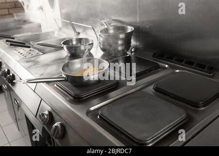 Cooking tasty pasta on stove in restaurant kitchen Stock Photo