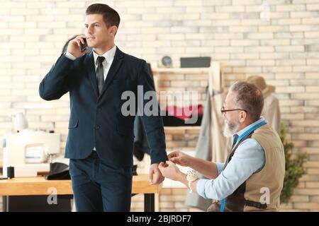 Senior man tailoring formal suit for businessman in atelier Stock Photo