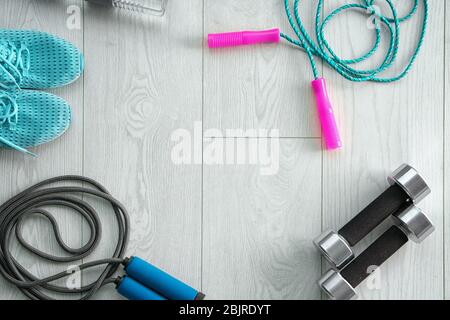 Jumping ropes, dumbbells and sneakers on wooden background, top view Stock Photo