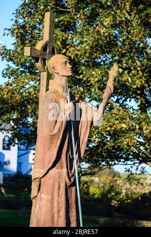 A modern statue of St Aidan of Lindisfarne next to the ruined Priory on Holy Island, Northumberland, England Stock Photo