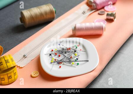 Pins and other tailoring items on fabric, closeup Stock Photo