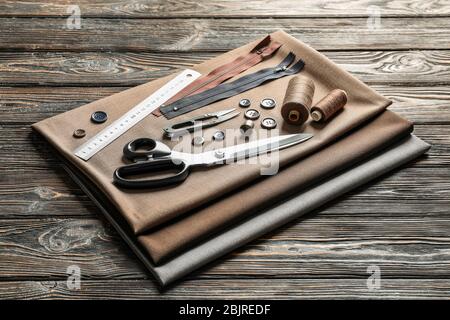 Set of tailoring tools, accessories and fabric on table Stock Photo