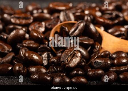 Close-up of brown, roasted coffee beans in a wood spoon background. Stock Photo