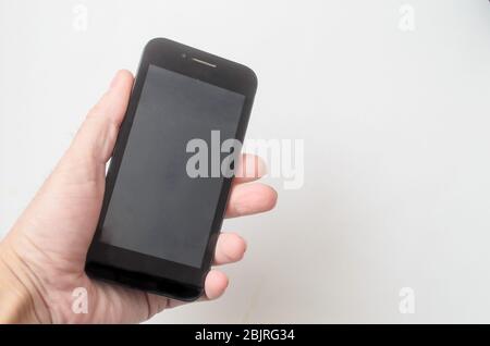 Man holds the smartphone in hand on white background.Space for text. Stock Photo