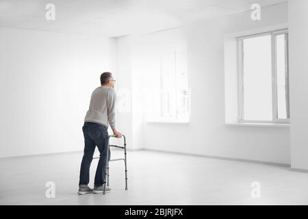 Senior man with walking frame in empty room Stock Photo