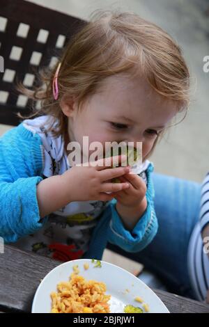 Toddler girl eating pasta and broccoli. Stock Photo