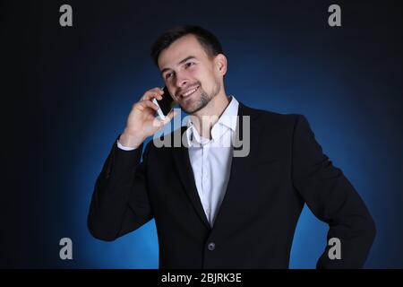 Man in formal suit talking on phone against dark background Stock Photo