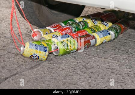 Cans of soda and beer placed on strings behind the wedding car. Stock Photo