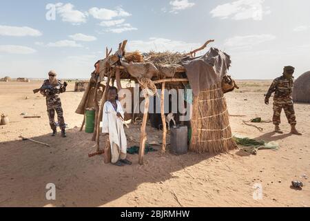 Agadez, Niger : military guard soldiers and African boy  traditional clothes in front of cattle shelter  in Sahara desert on the board Stock Photo