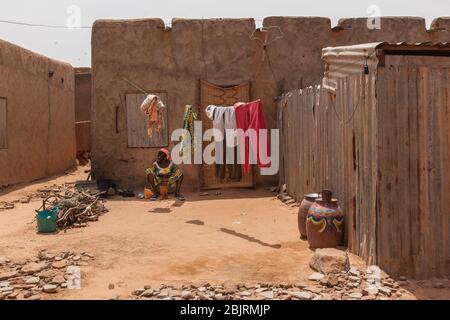 African woman washing clothes in yard old city center street mud houses Stock Photo