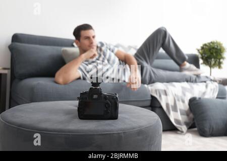 Young man posing on couch for professional camera indoors Stock Photo