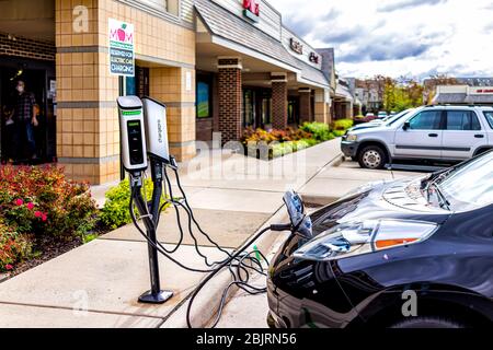 Herndon, USA - April 27, 2020: Virginia Fairfax County building exterior sign in parking lot for electric car charging of Mom's Organic Market store s Stock Photo