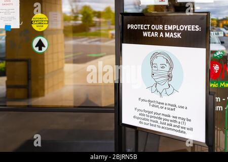 Herndon, USA - April 27, 2020: Virginia Fairfax County building exterior sign entrance to Mom's Organic Market store with request to wear face mask at Stock Photo