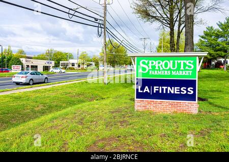 Herndon, USA - April 27, 2020: Entrance to plaza on street in Virginia Fairfax County with sign for Sprouts Farmers Market and LA Fitness Gym Stock Photo