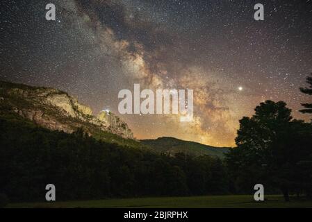 A group of climbers near the top of Seneca Rocks in West Virginia, as twilight ends and the Milky Way makes an appearance high above the mountains. Stock Photo