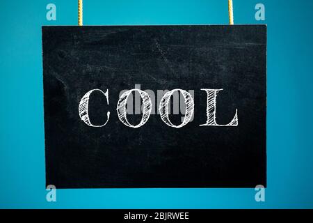 Chalk board is hanging with the inscription "cool" on a blue background. copy space Stock Photo