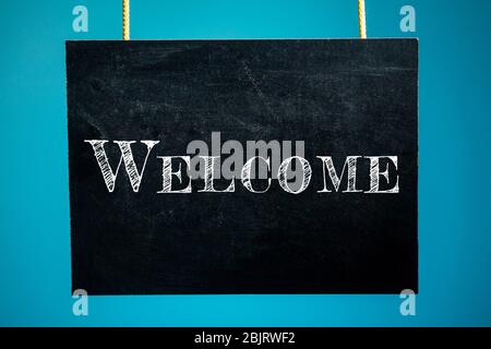 Chalk board is hanging with the inscription 'Welcome' on a blue background. copy space Stock Photo