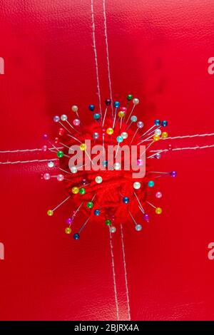 a red skein of thread stuck a lot of needles on red leather. close up copy space Stock Photo