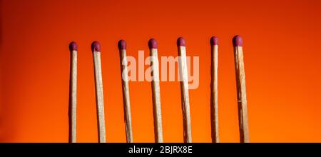 seven matches with a red head in a row on a Lush Lava background. close up copy space Stock Photo