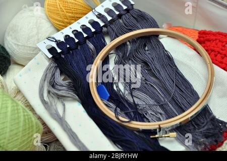 Homemade needlework. Embroidery kit, linen, hoop, multi-colored threads. Stock Photo