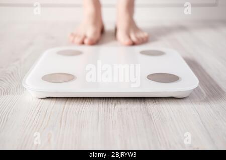 Woman foot takes a step onto a smart scale that makes bioelectric impedance  analysis, BIA, body fat measurements. Stock Photo