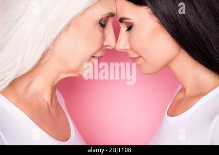 Cropped close-up profile side view portrait of two nice attractive lovely cute sweet peaceful women family values touching foreheads isolated over Stock Photo