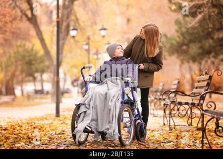 Little boy in wheelchair with sister outdoors Stock Photo