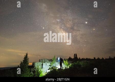 A night sky photographer sets up the camera to get a shot of the milky way above the rocky landscape on Dolly Sods in West Virginia. Stock Photo