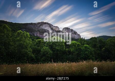 Fireflies fill the edges of the field and forest surrounding Seneca Rocks on an early summer evening in the West Virginia mountains. Stock Photo