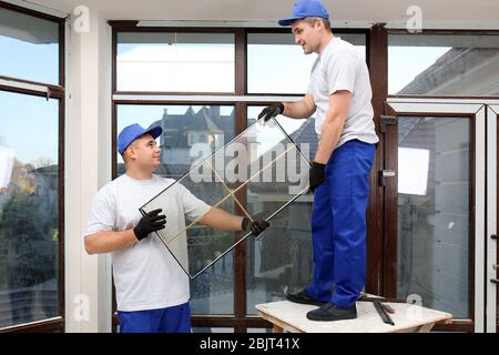 Construction workers repairing window in house Stock Photo