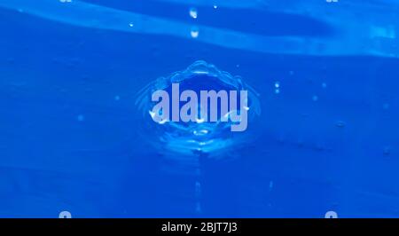 a drop falls into blue water Stock Photo