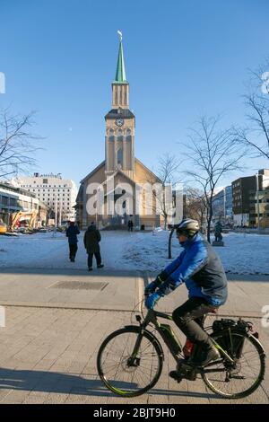 Man on a bicycle riding past Tromsø Cathedral, Tromsø, Norway Stock Photo