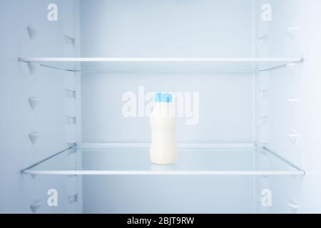 Bottle of milk in empty refrigerator Stock Photo