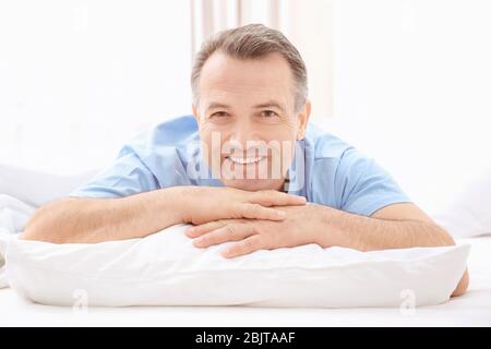 Mature man lying on white pillow indoors Stock Photo