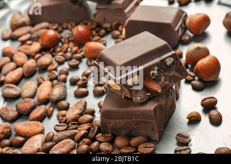 Pieces of chocolate, hazelnuts, cocoa and coffee beans on metal tray, closeup Stock Photo