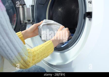 Young woman doing laundry in laundromat Stock Photo