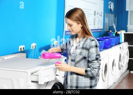 Young woman doing laundry in laundromat Stock Photo