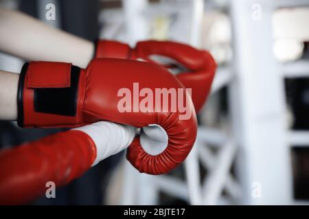 Boxer holding hands in gloves on rope of boxing ring Stock Photo