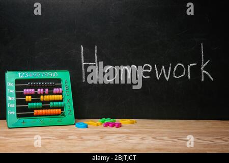 Abacus on table near chalkboard with word "Homework" Stock Photo