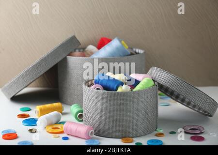 Boxes with color sewing threads and buttons on table Stock Photo
