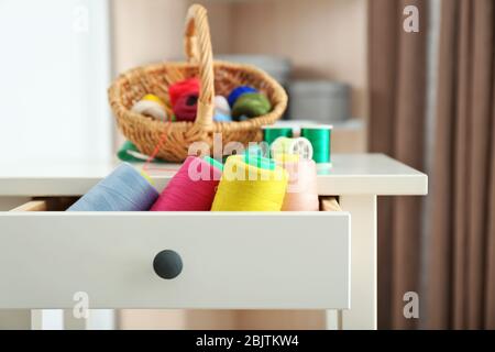 Set of color sewing threads in drawer of small table indoors Stock Photo