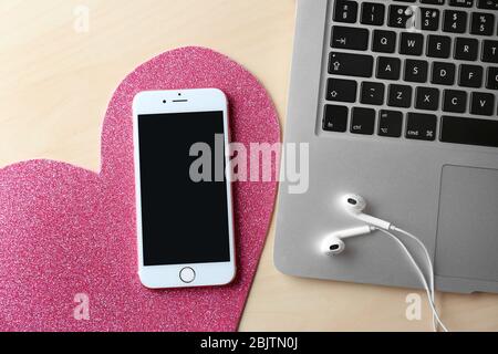 KYIV, UKRAINE - NOVEMBER 28, 2017: iPhone 6s Plus Rose Gold with blank screen, earpods and laptop on table Stock Photo