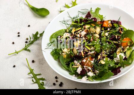Salad with beetroot, avocado, feta cheese, rucola, tomato, various greens, pumpkin seeds in a white bowl. Diet healthy food for weight loss. Close-up. Stock Photo