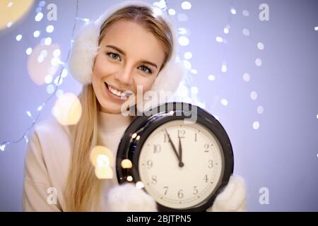 Happy woman with clock against blurred lights Stock Photo