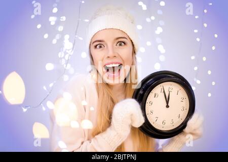Happy woman with clock against blurred lights Stock Photo