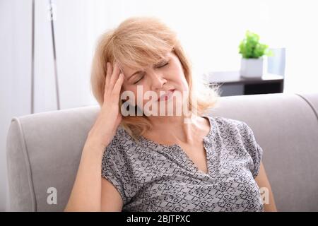 Mature woman suffering from headache at home Stock Photo