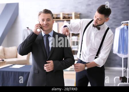Tailor taking man's measurements in atelier Stock Photo