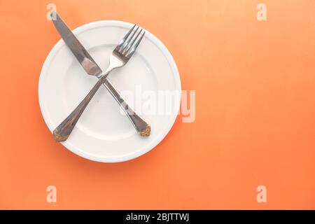 empty plate with fork and knife on orange . Stock Photo