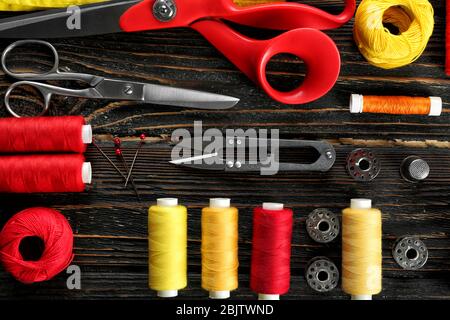 Composition with sewing threads and accessories on wooden background, top view Stock Photo
